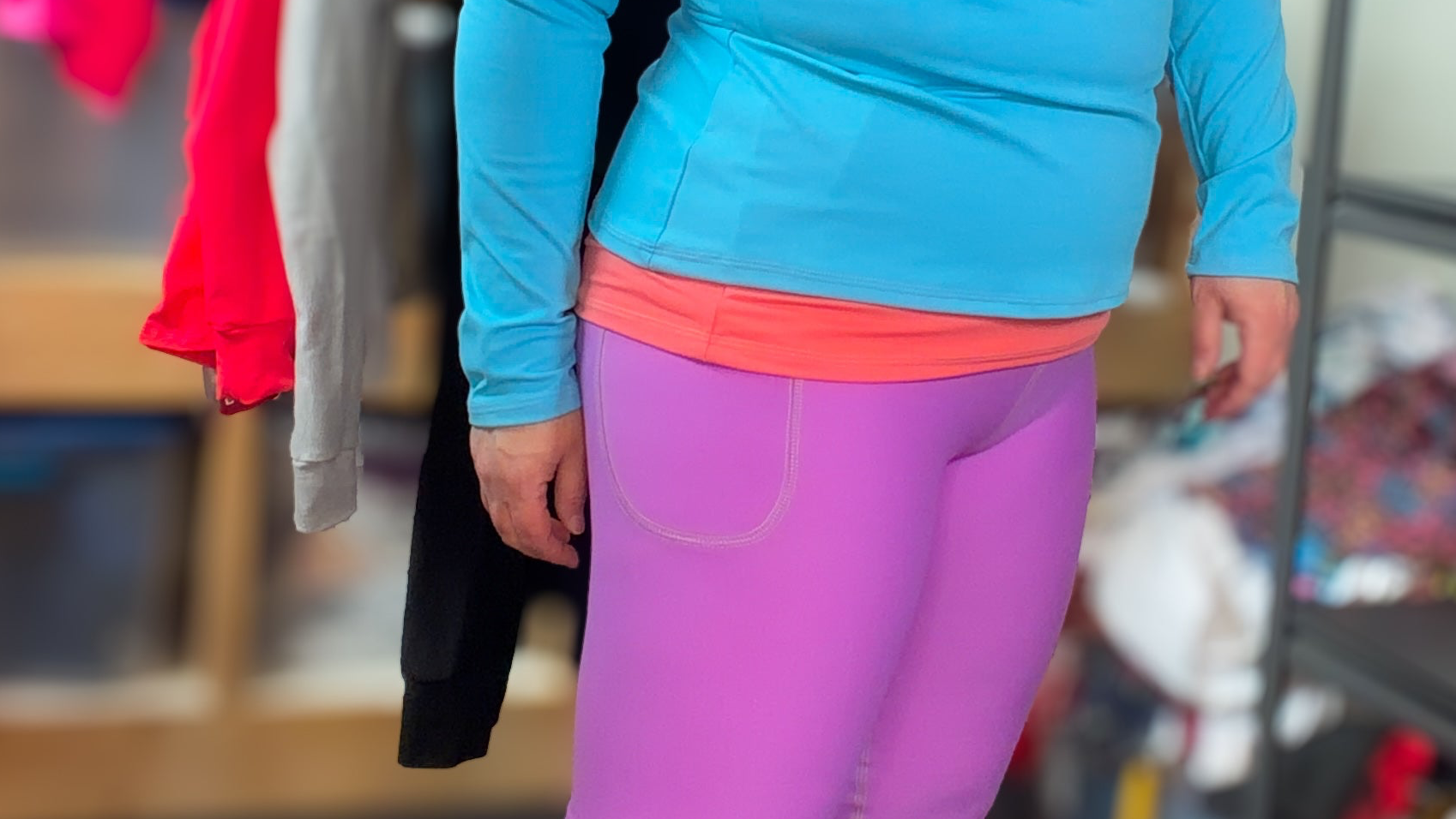 Person wearing bright blue top and purple leggings in a store setting